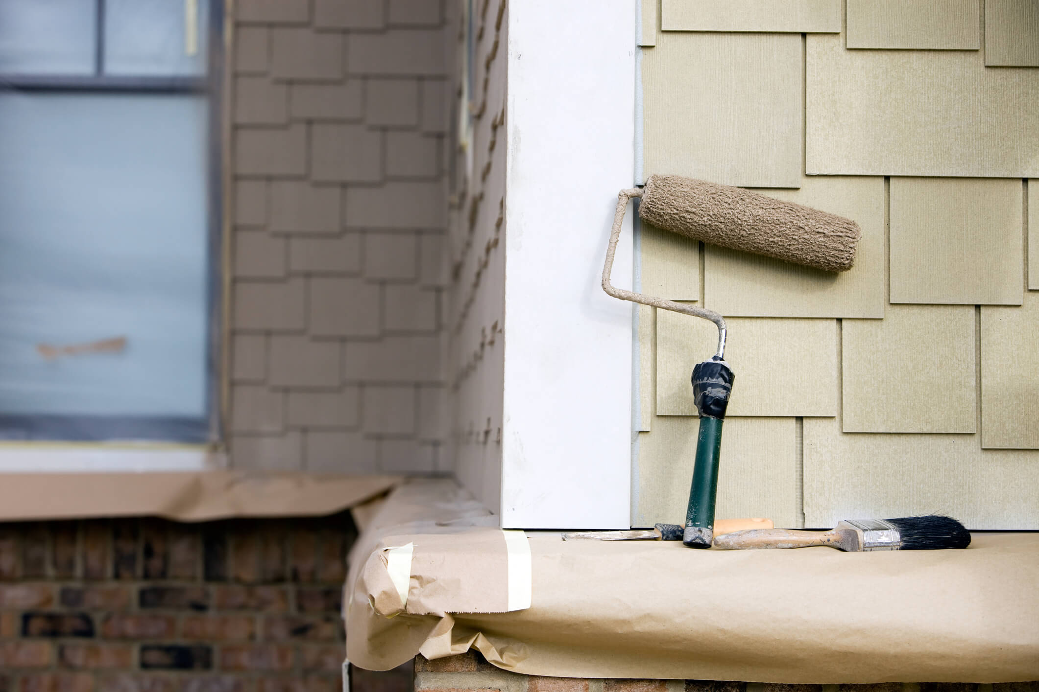 Shingles on home being painted with a roller