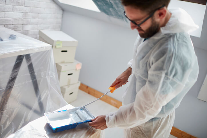 A professional commercial painter preparing to paint walls of a new office space with a roller of paint