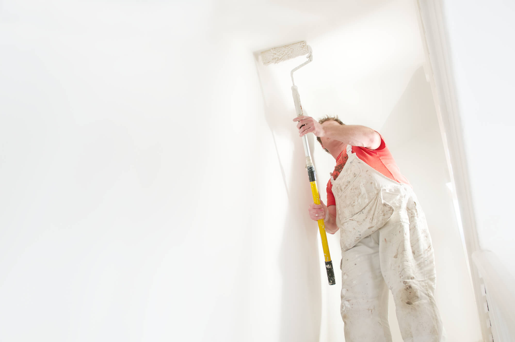 Man painting the inside of a commercial building with a roller brush