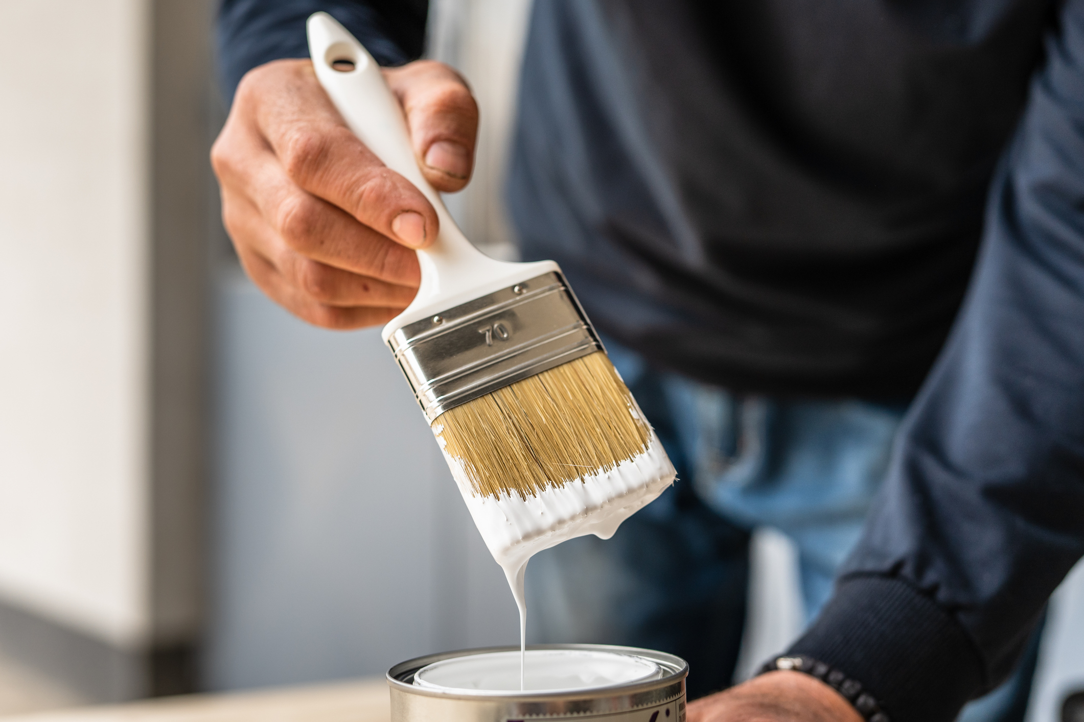 Close-up-on-white-paint-brush-in-the-hand-of-unknown-man-painting-house