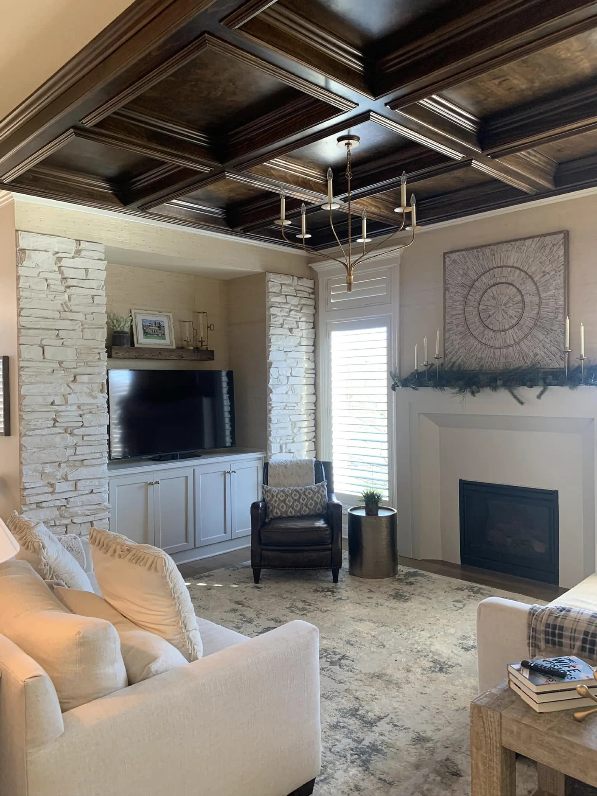 a family room features updated built ins with white painted tv cabinets and fireplace mantle. The painted woodwork contrasts the newly refinished natural wood ceiling beams. This blend of mixed wood finishes is continued throughout this renovation's design by providing variety within unity.