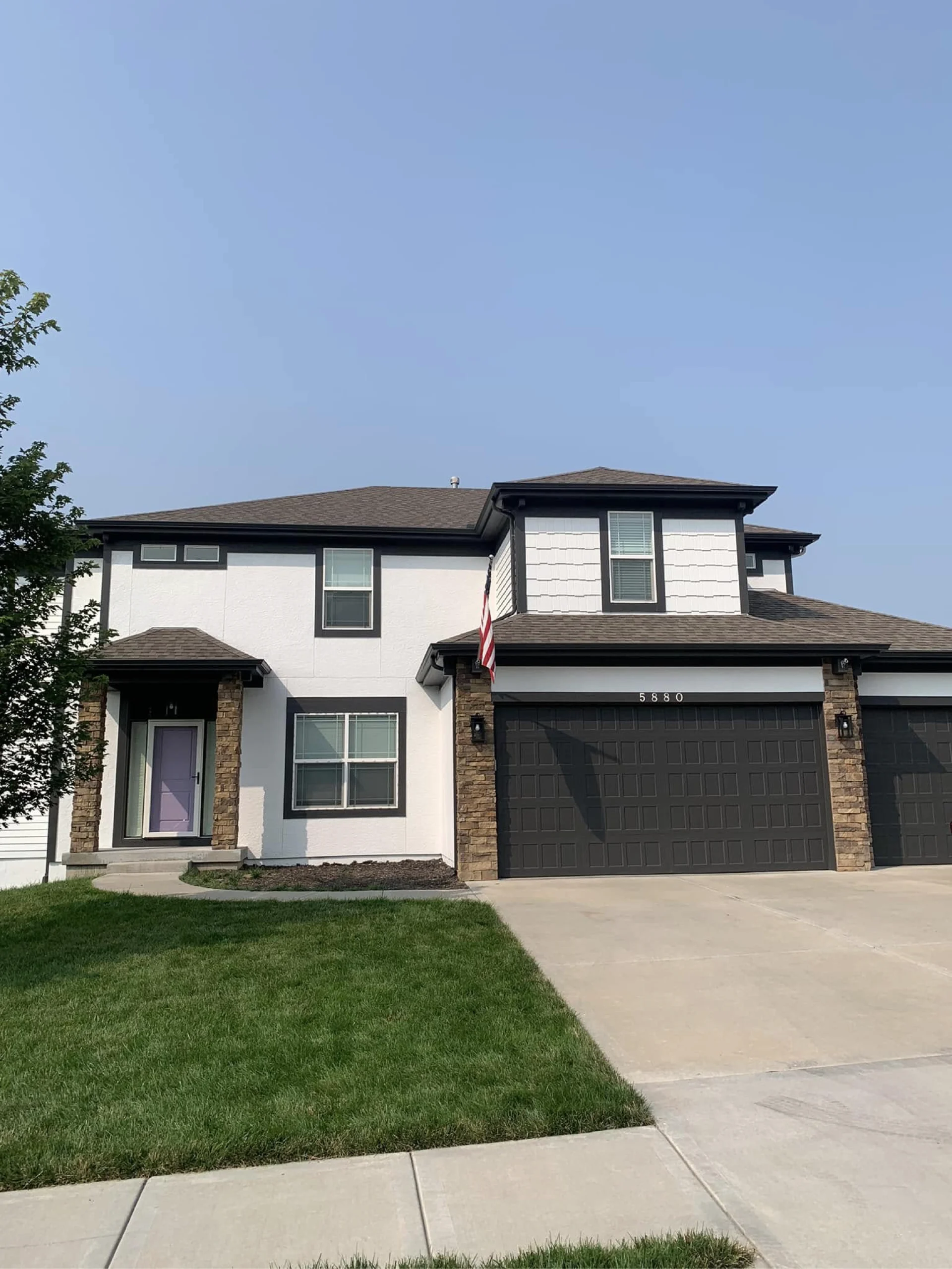 this home's exterior is updated with a black and white color palette and fun light purple front door