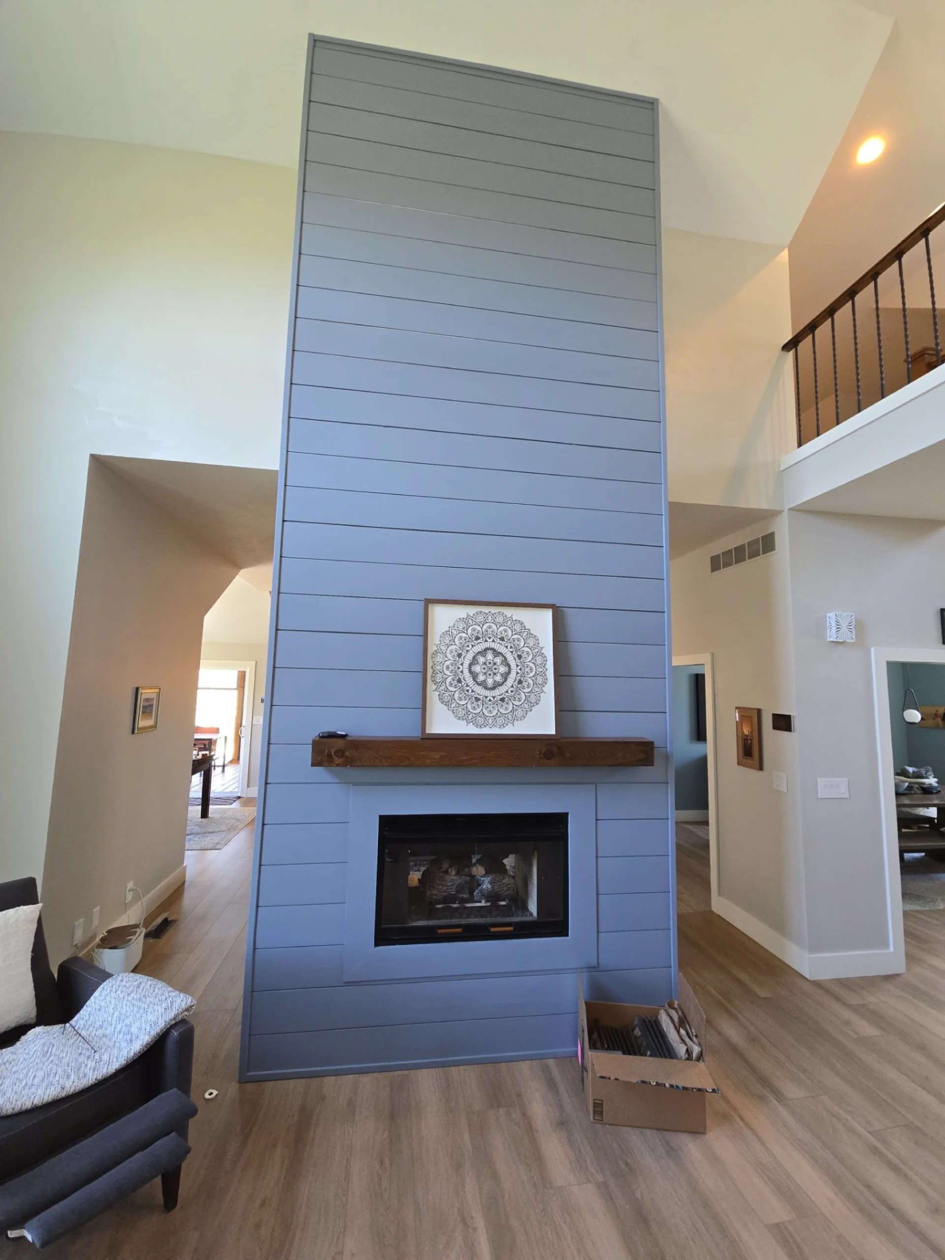 professionally painted two story grey wood paneled fireplace and natural wood stained mantle