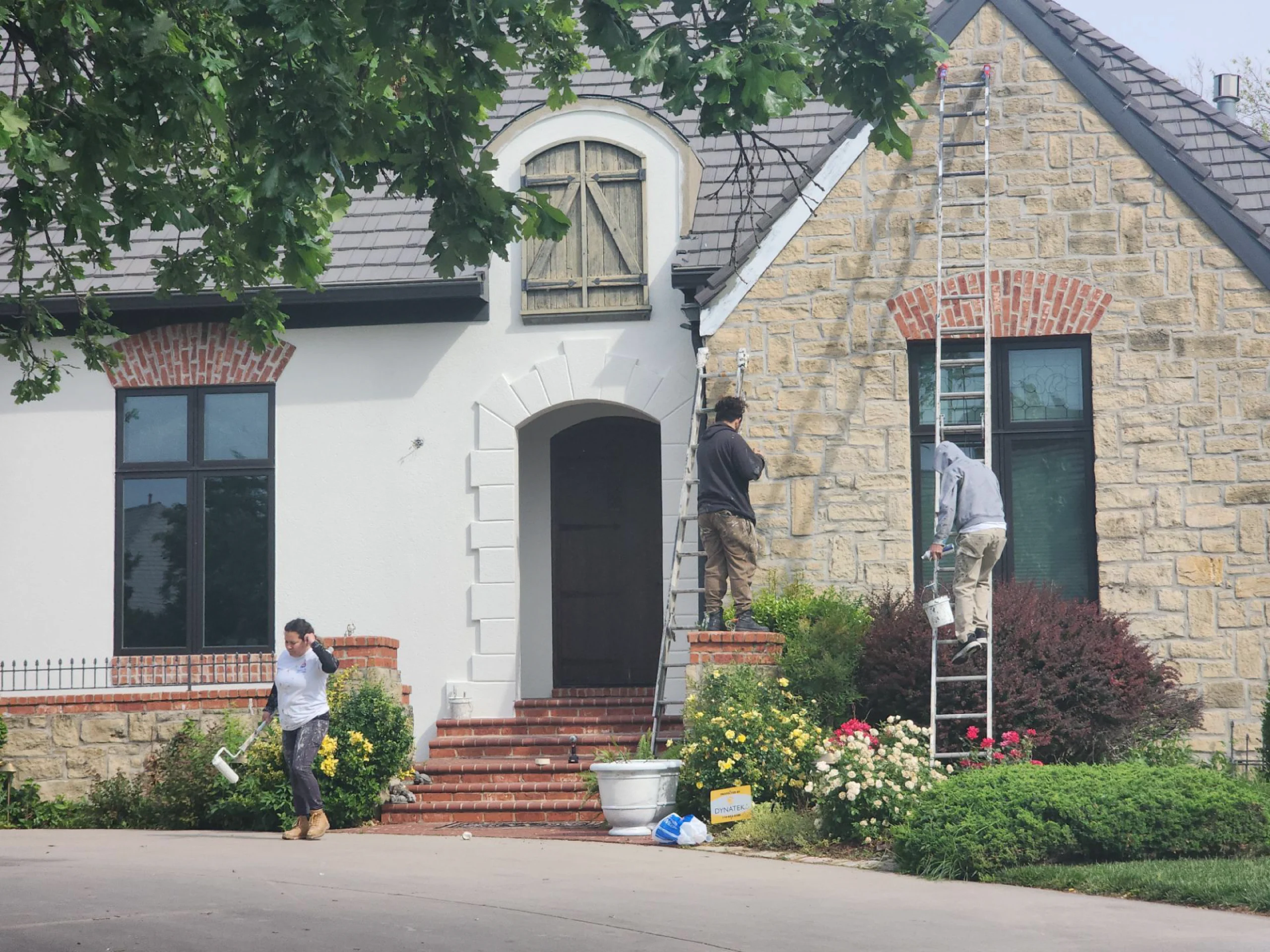 three Professional Painters from the River City Painting Team work together painting the stucco, stone, and brick exterior of this residential home to a fresh and clean modern white