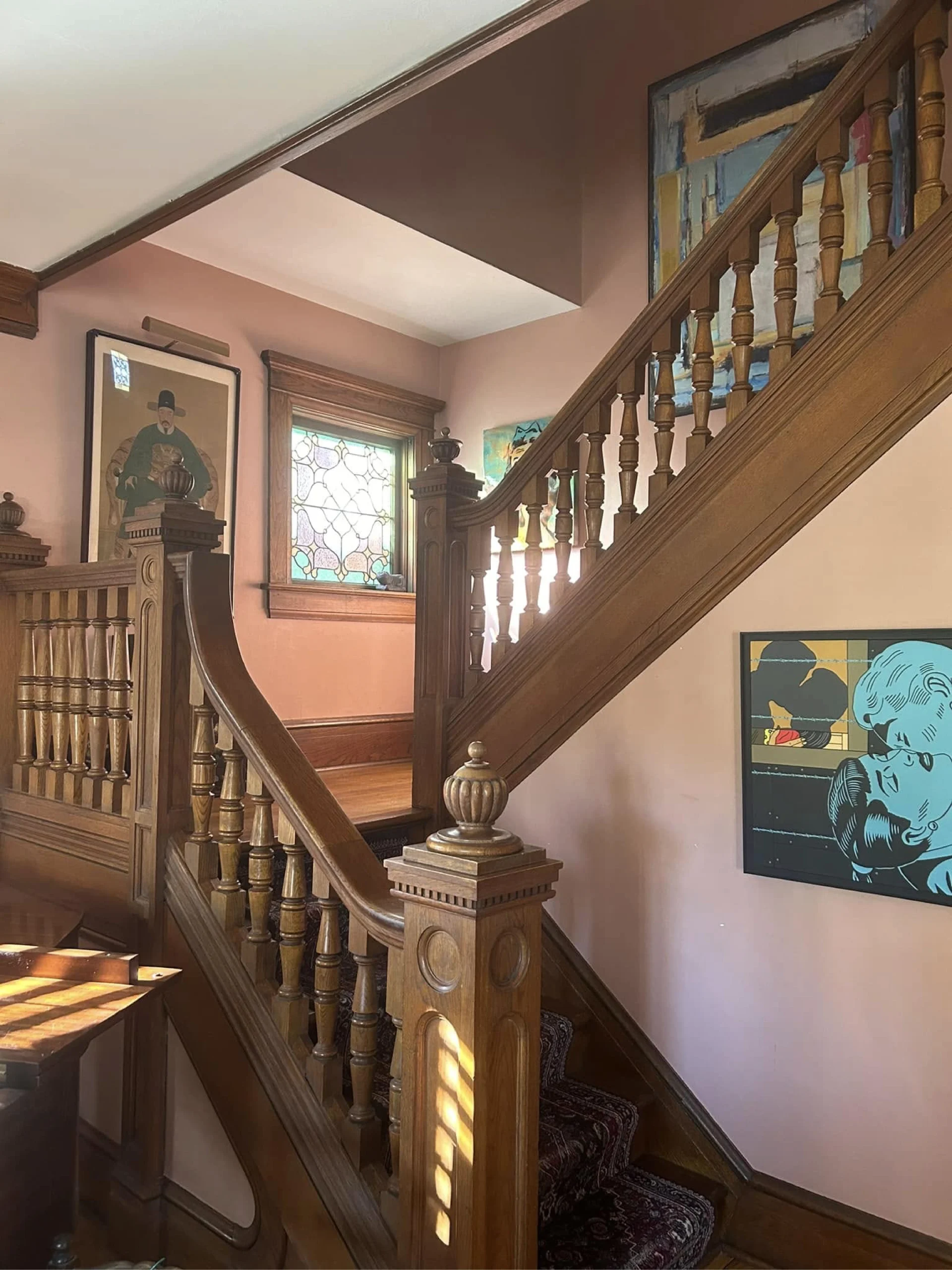 a historical home with impressive woodwork stands out with professionally painted pink walls that highlight the client's artwork and stained glass window